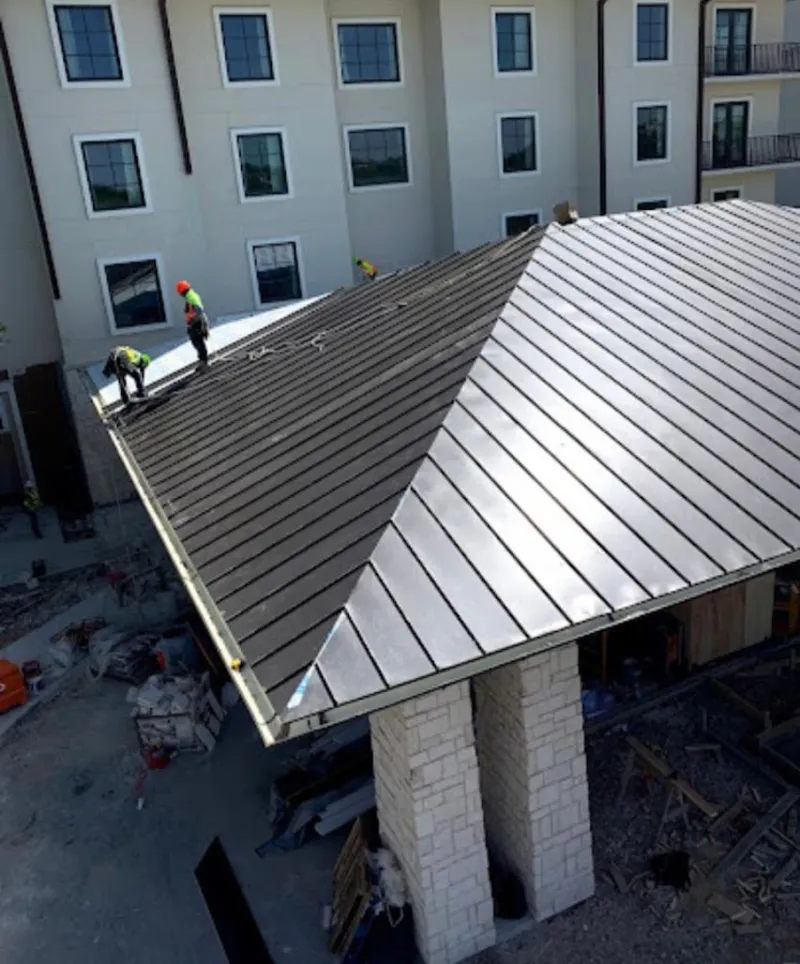 Crew installing standing seam metal roof panels on a commercial project in Altadena